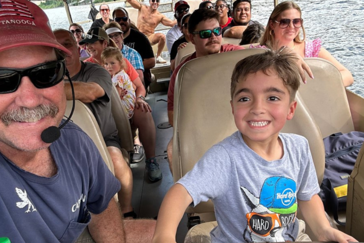 People on a boat, smiling boy in front, captain wearing headset.