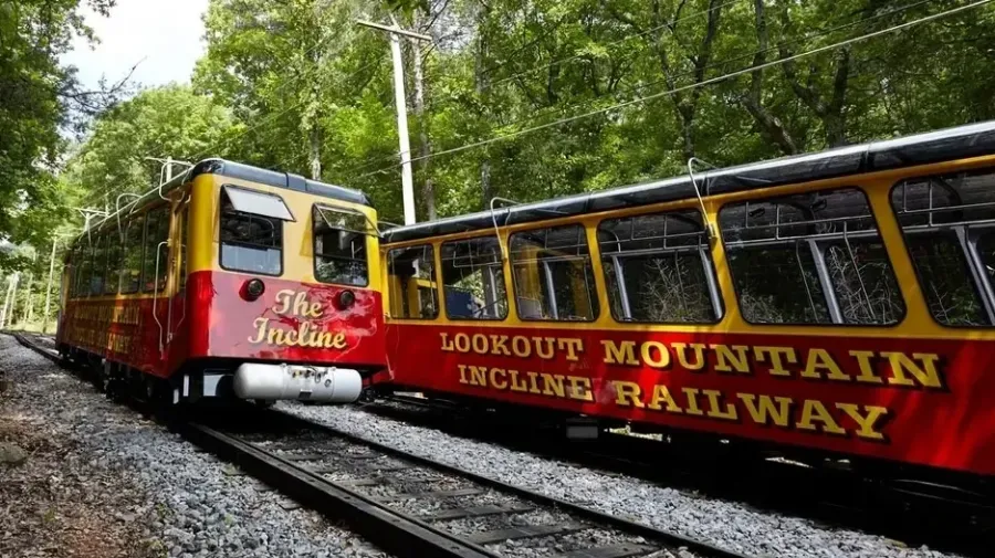 Red and yellow train on Lookout Mountain Incline Railway tracks through lush green trees.